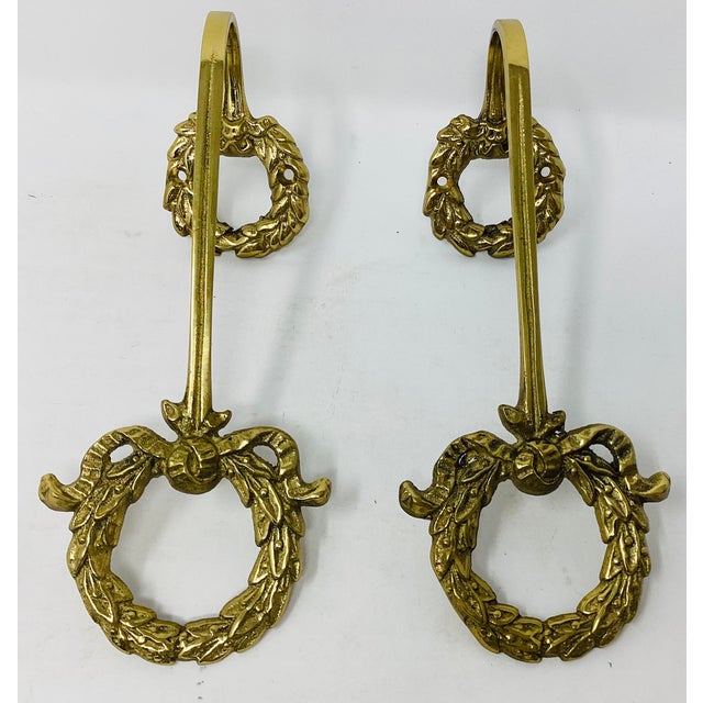 Pair of brass curtain holdbacks with a beautiful wreath and ribbon design.