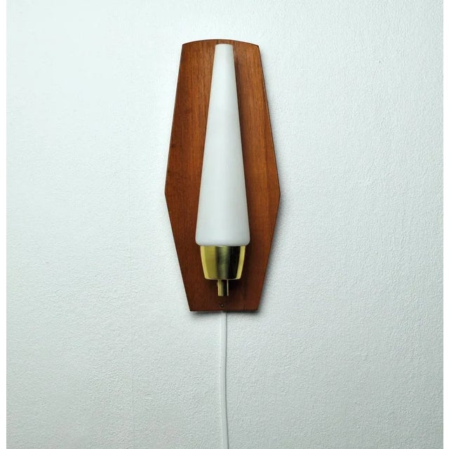 Mid-Century Modern wall light in a slightly bowed teak, brass and opaline glass shade. Probably made in Denmark the 1960s....