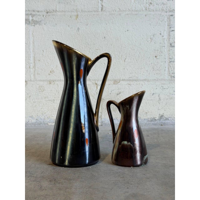 This pair of versatile ceramic pieces seamlessly doubles as either small bud vases or candleholders, showcasing a striking...