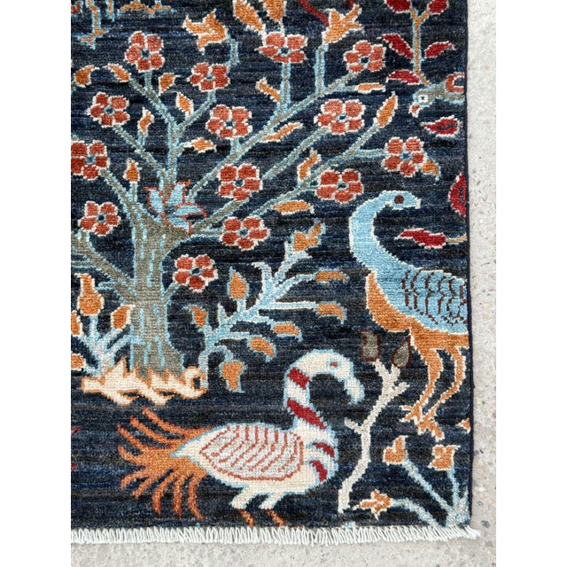 A hand-knotted Tree of Life rug, woven in Afghanistan on a deep indigo ground and filled from edge to edge with a garden...