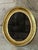 This antique oval wall mirror is an elegant testament to early 20th-century craftsmanship and refined design. The frame is...