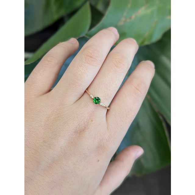 A rare tsavorite garnet rests in a vivid grass green at the centre of this solid 14K yellow gold ring, surrounded by four...