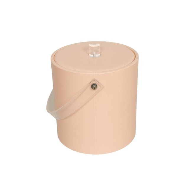 A mid century ice bucket in blush. The lid is padded with a cylindrical Lucite knob handle at the center. The bucket has a...