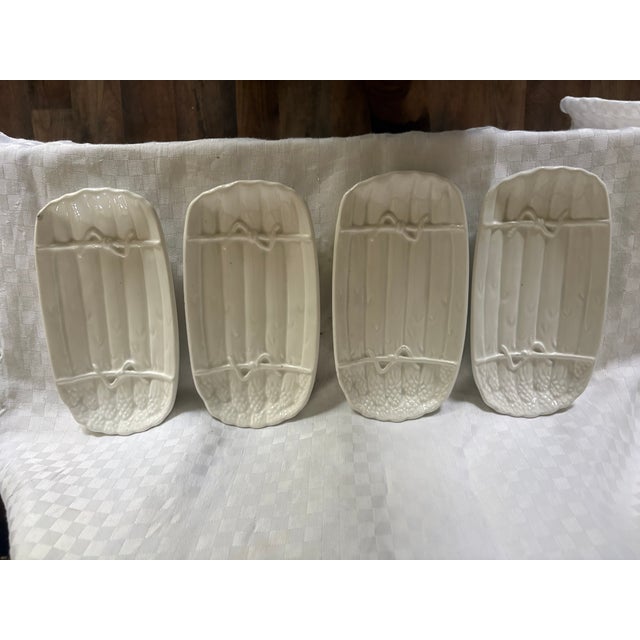 A set of 6 oval ceramic plates with an asparagus motif. The plates are cream colored and are. not marked. Each plate...