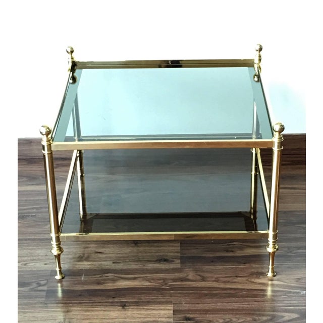 French vintage square coffee table in solid gilt brass with two glass shelves and ball finials. Iconic Maison Baguès...