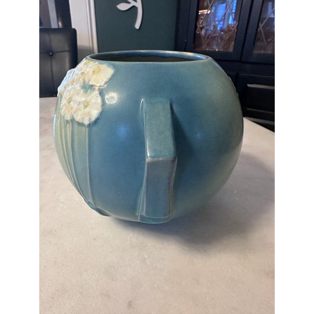 The Roseville Pottery Primrose Art Deco Jardinier Vase in blue, made in 1932, is a vintage piece of North American art...