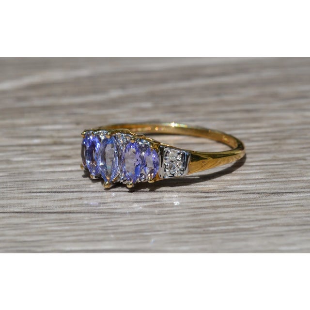 The Campanilla Ladies Yellow Gold Cocktail Ring set with Marquise Cut Tanzanite and Diamonds. Crafted in desirable yellow...