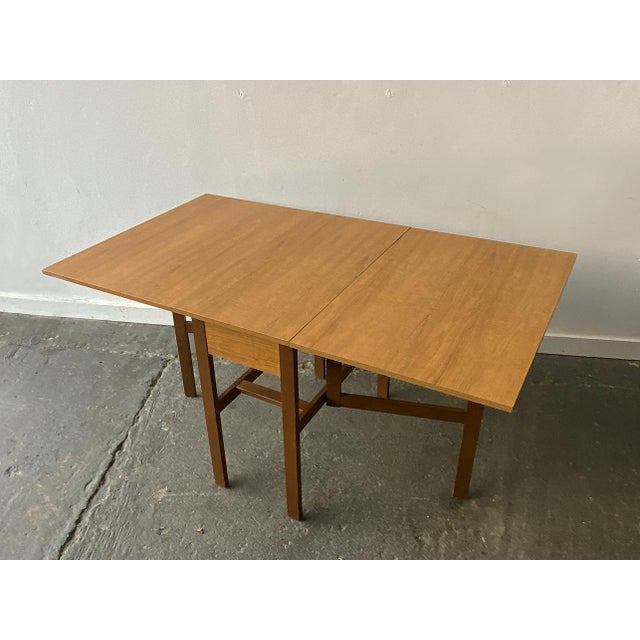 A wide and substantial extending dining table with the original wood grain laminate table top and 2 drop leaves. Supported...