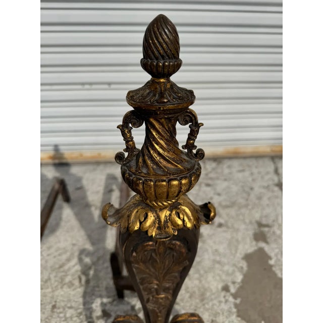 This pair of andirons was made in Italy circa 1820. Its made of wrought iron and has gilt accents. The finial is a gilt...