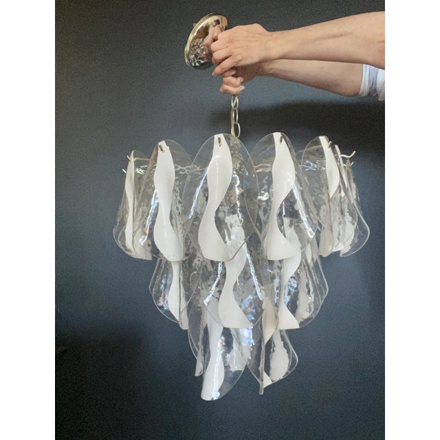 Clear acrylic “petals” with off white detailing cascade like a waterfall delicately down a chrome base chandelier. Six...