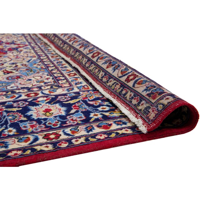 Beautiful Vintage Persian Kashan hand-knotted wool rug has a red field with navy blue frame and multicolor accents in a...