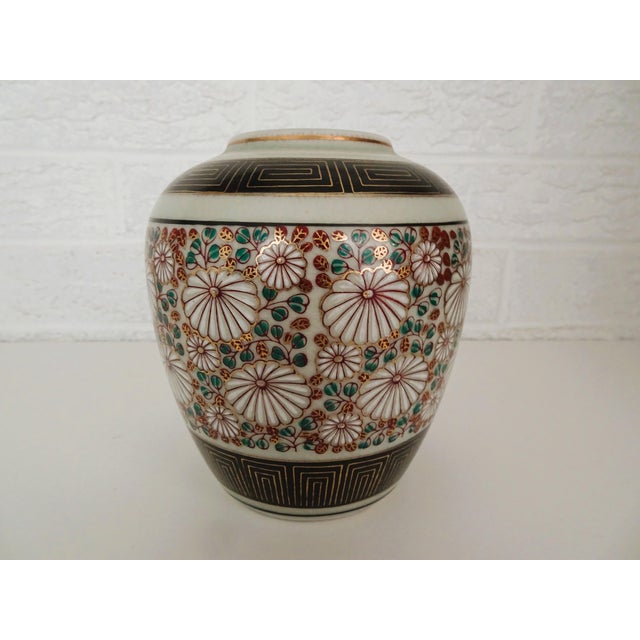 This vase is done in a floral motif and is very colorful. Hand painted and with a gold on black band top and bottom of the...