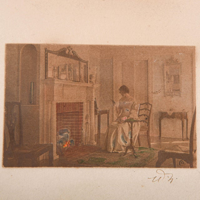 This Framed Signed Wallace Nutting (1861-1941) Hand-Colored Print captures a quiet domestic moment in a warmly appointed...