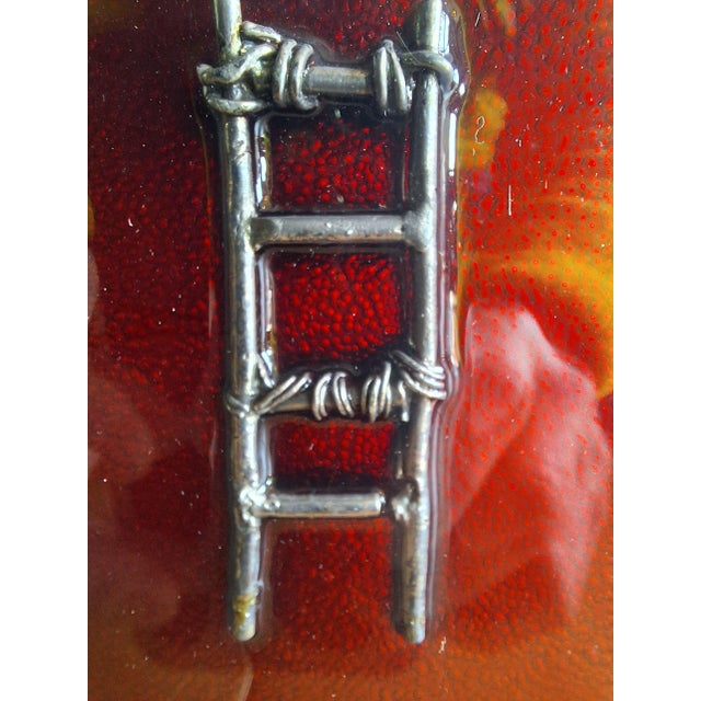 The work is a sculpture made of cast silver metal submerged in fire-red enamel, depicting a ladder. The work is housed in...