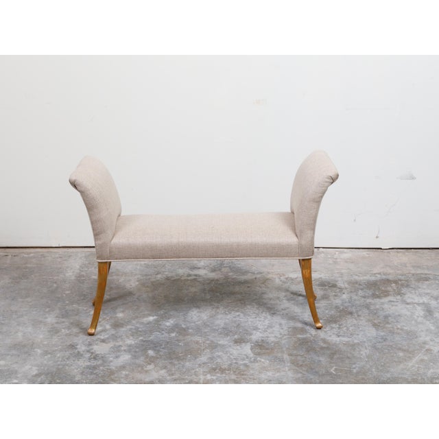 A French giltwood bench from the mid 20th century, with out-scrolling arms, saber legs and new upholstery. Created in...