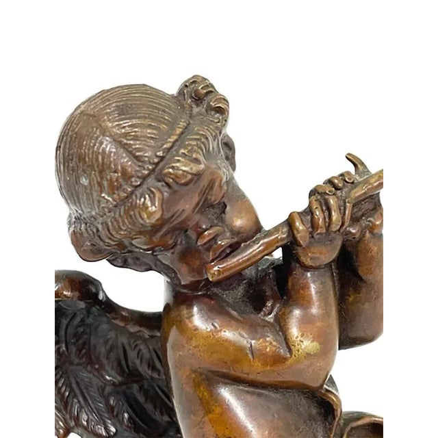 A small French19th Century bronze statuette of a putti playing the flute standing on a cloud, dancing with a ribbon in his...