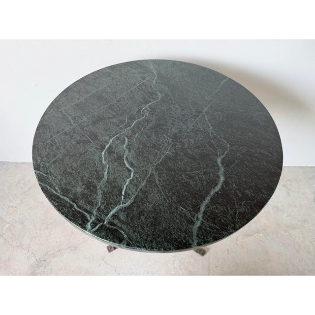 A striking vintage Art Deco-style side table featuring a richly veined dark green marble top resting on a hand-wrought...