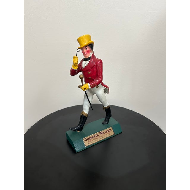 A circa 1950s Johnnie Walker “Striding Man” advertising figurine, produced in the United Kingdom as branded whiskey...