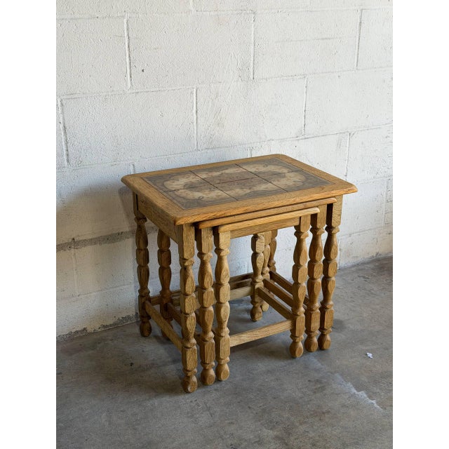 Turned spindle legs support patterned ceramic tile tops in a space-saving set of three nesting tables. Their compact...