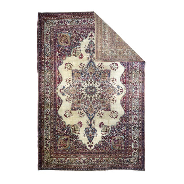 This finely woven SE Persian city carpet shows a shaped and indented ecru-beige semi-open field centered by an octogramme...