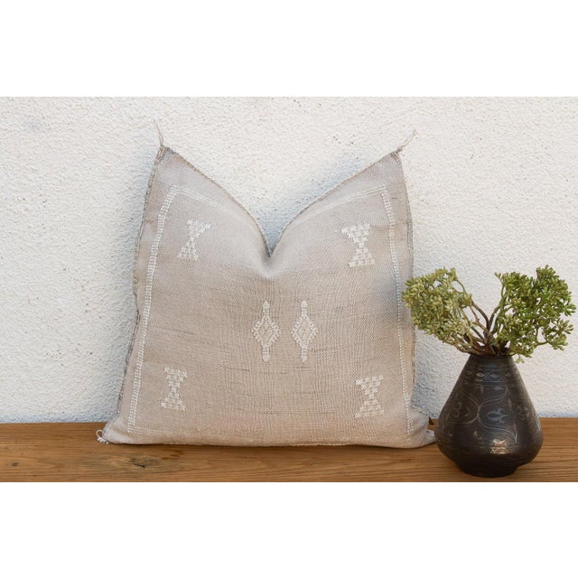 A geometric medallion band runs through the center of this handcrafted Moroccan cactus silk pillow, bordered by fine...