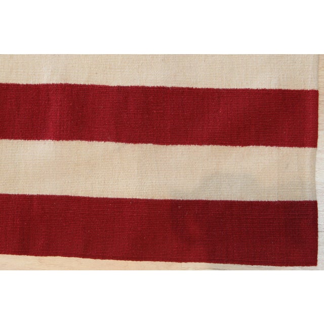 A handwoven wool flatweave with a stars-and-stripes flag design, made in China and measuring 5' x 8'. With no pile, the...