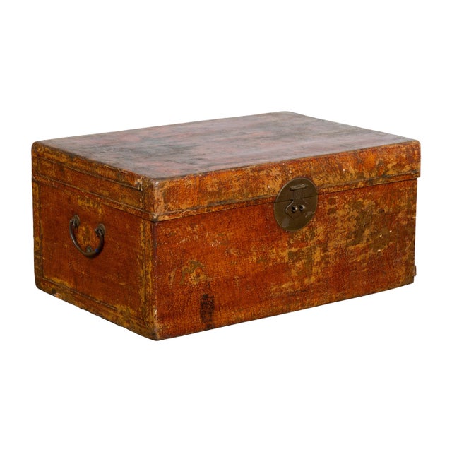 A Chinese antique Qing Dynasty period storage trunk from the 19th century made of red lacquered leather with distressed...