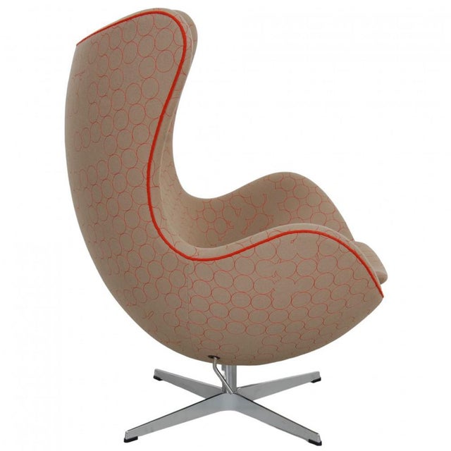 Arne Jacobsen Egg chair upholstered in original beige fabric with an orange and red pattern. The chair is from 2014 and...