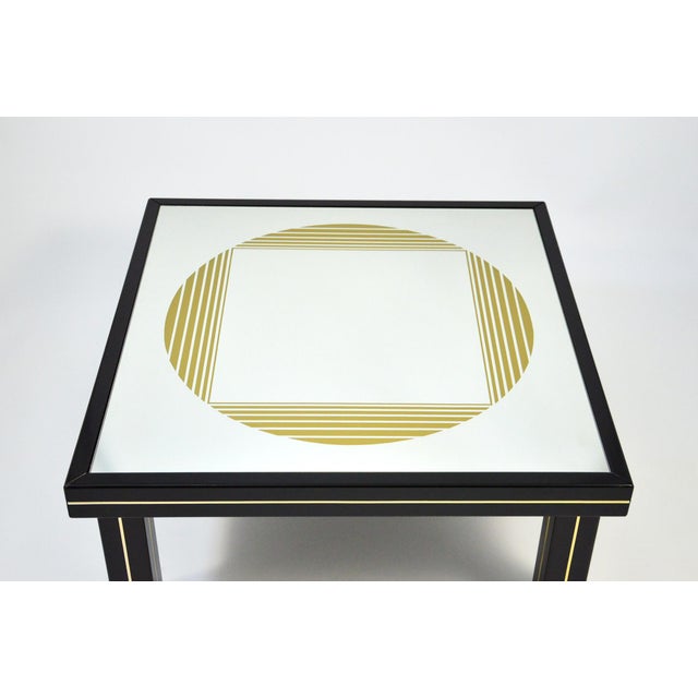 Black lacquered wood coffee table with brass trim and gold silk-screened mirror top, designed in the 1970s by Gianni...