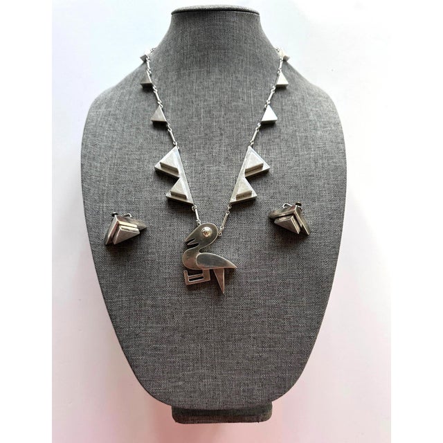 A highly sculptural sterling silver jewelry suite consisting of a necklace with bird pendent and a matching pair of...