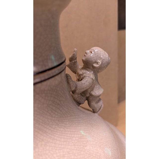 Ceramic, with two Chinese figures. Cream/tan with cracklature glaze and wooden base. Approx. 9”w x 29.5” h; note: no...
