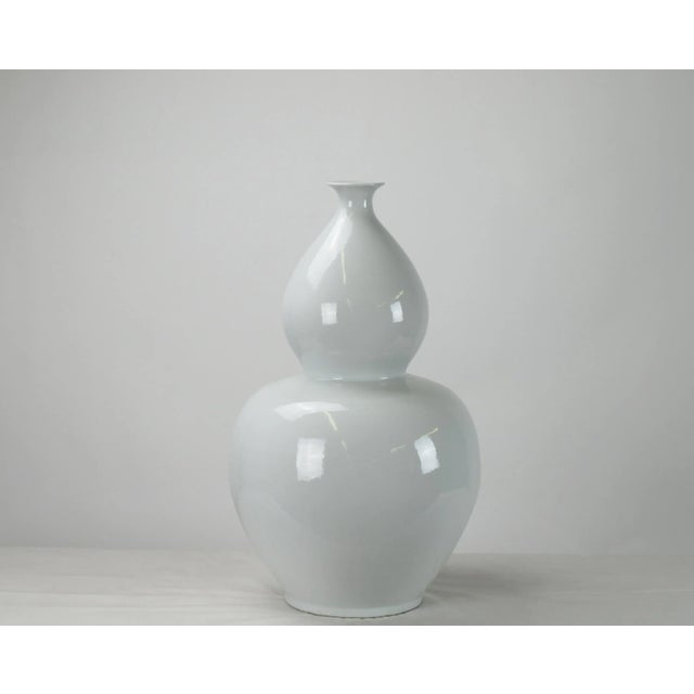 A symbol of immortality and happy life, this large bottle gourd vase with glossy white finish has smooth curving...