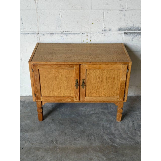 This versatile oak storage cabinet features two paneled doors opening to an internal shelf for storage. Elevated on...