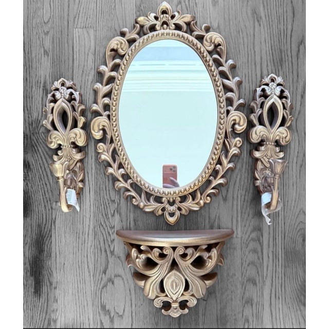 Decorative oval mirror with matching wall sconces and coordinating shelf. Intricate carved scrollwork and fleur-de-lis...