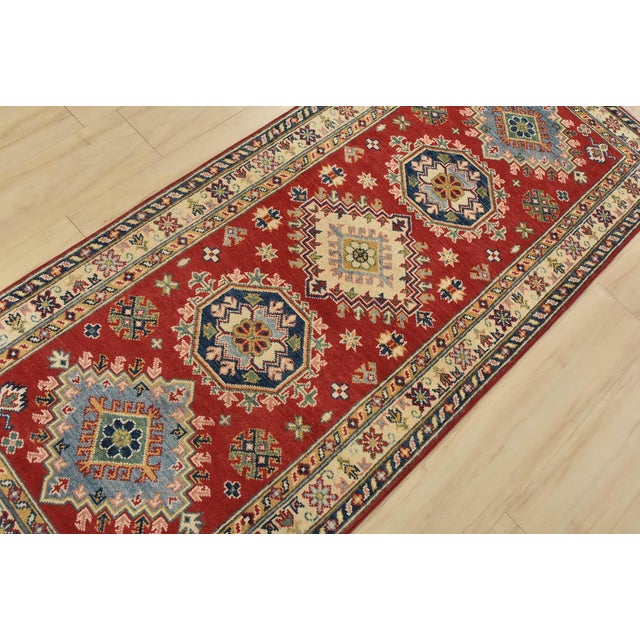 A tribal Caucasian Kazak runner hand-knotted with fine wool on a cotton foundation. This rug features a row of geometric...
