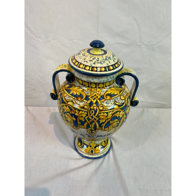Hand painted blue urn with scrolled handles featuring a delicate design in shades of blue and yellow. Hand made items may...