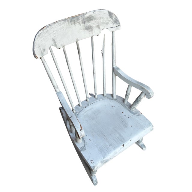 Charming vintage child-size wooden rocking chair featuring a classic Windsor-inspired spindle back, curved arms, turned...