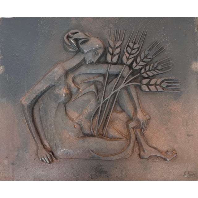 This modernist fireback is made of cast iron. It depicts a nude woman with a scythe and ears of wheat. It is a French work...