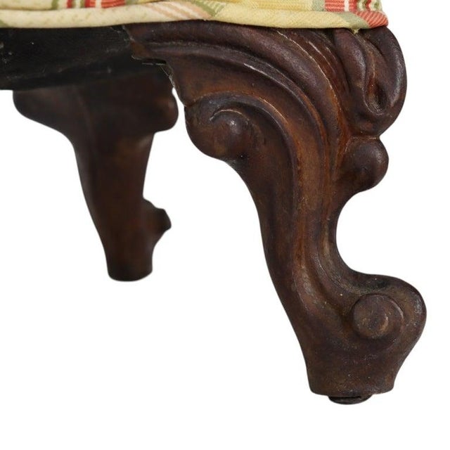 This antique footstool, dating to approximately 1920, features a rectangular upholstered cushion set upon a frame with...