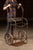 Riveted and welded steel cylinder cart featuring spoked cast-iron wheels, a curved handle frame, and an original safety...
