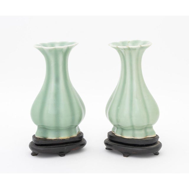 Pair of Chinese Celadon Glazed Porcelain Yuhuchunping Vases, each of lobed pear vase form and with carved wood stand....