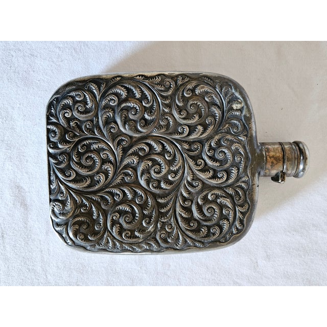 An Antique 1890 Derby Silver Company Silver Plated Whiskey Flask. Featuring attractive fern scroll pattern in high relief....