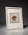 Decorative framed floral wall art featuring red poinsettia-style flowers in a blue pot with a soft green leaf wreath...