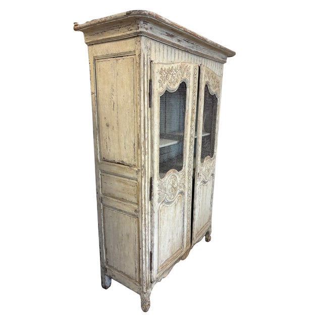 A beautifully aged antique French provincial armoire showcasing hand-carved floral detailing, elegant proportions, and a...
