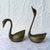 A graceful pair of vintage brass swan sculptures showcasing elegant Art Deco-inspired silhouettes and a naturally aged...