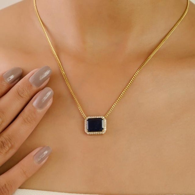 This exquisite necklace features a 4.08 ct natural emerald-cut blue sapphire centerpiece 11.22 x 9.18 mm, framed by a halo...