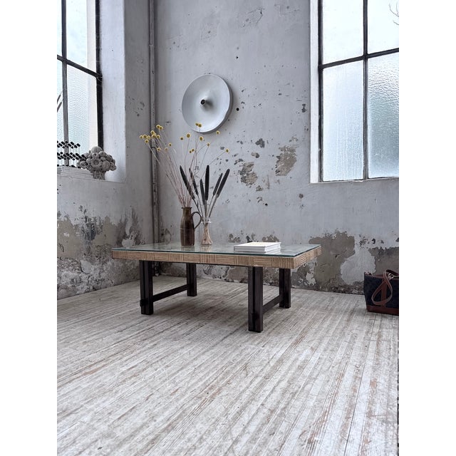 Vintage coffee table with a sculpted composite-stone top, resembling ceramic. It rests on a clean-lined metal base,...