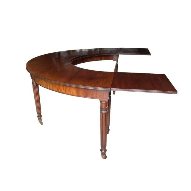 REGENCY MAHOGANY HUNT TABLE CIRCA 1810 The demi-lune top forming a crescent, each end united by a brass rail. This table...