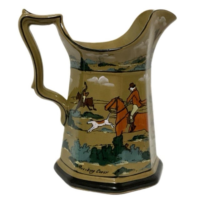 Decorative hunting pitcher or jug, 8 sided with a flared spout, angular handle, and dark-edged foot. Fox hunting scenes on...