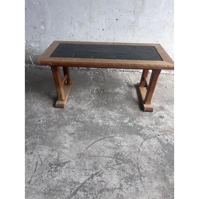 Sculptural vintage coffee table made from solid oak, featuring a dark slate inset decorated with engraved zodiac-inspired...